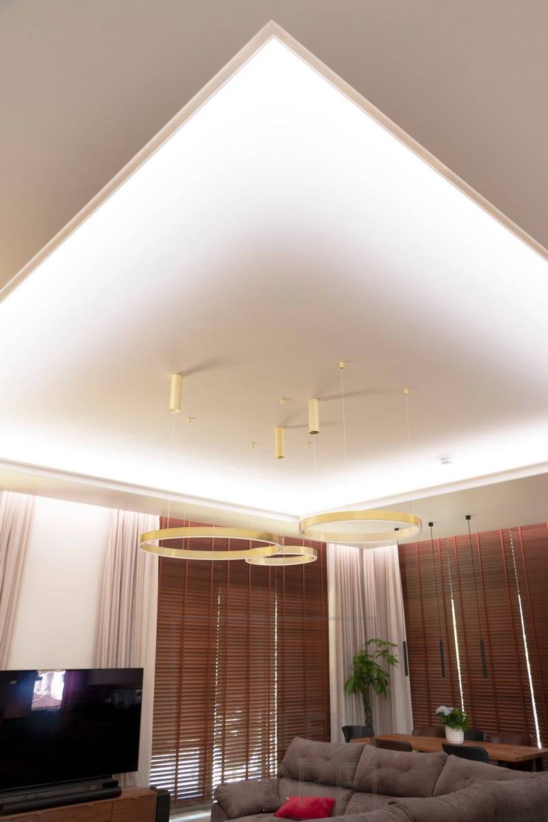 Magnifique éclairage indirect de style hôtelier avec une bande LED montée à la fois entre le plafond et le mur et sur la guillotine du downlight. Cela permet d'obtenir un éclairage d'ambiance dans deux directions dans l'espace. La bande LED au plafond crée un plafond lumineux dans le salon et le rail du rideau est magnifiquement caché dans la même rainure que la bande LED.